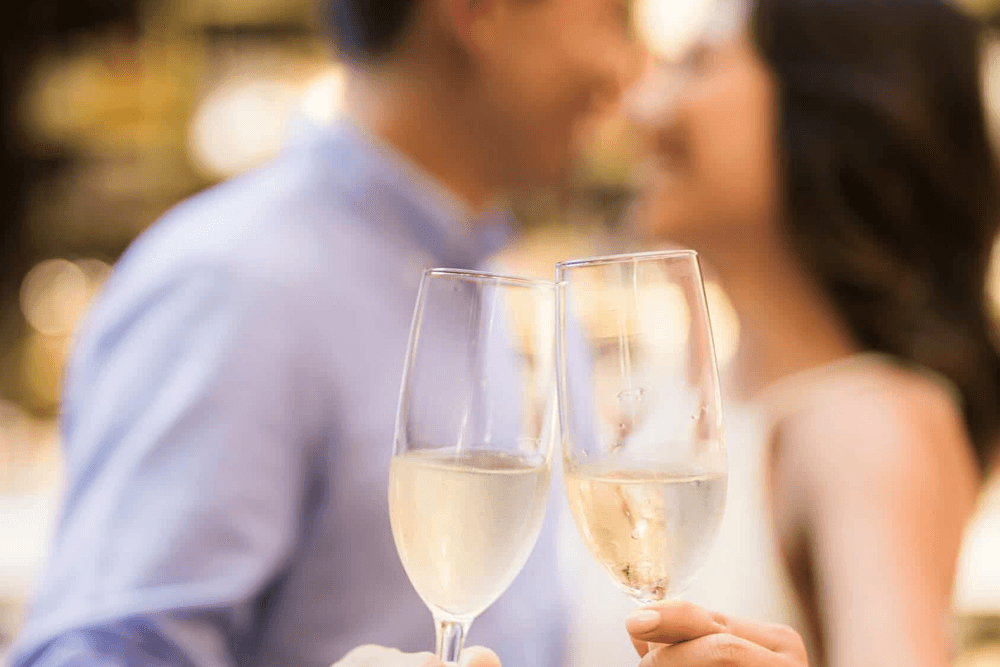 A couple clinks champagne glasses in celebration.